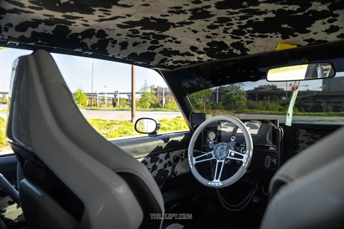 Interior view showing the cow-print upholstery and Corbeau seats, matching the car’s “Milk Money” nickname.