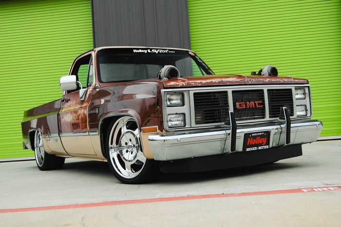 Front 3/4 view of the JourneyHQ 1983 GMC C10 showing patina paint and turbo hood cutouts.