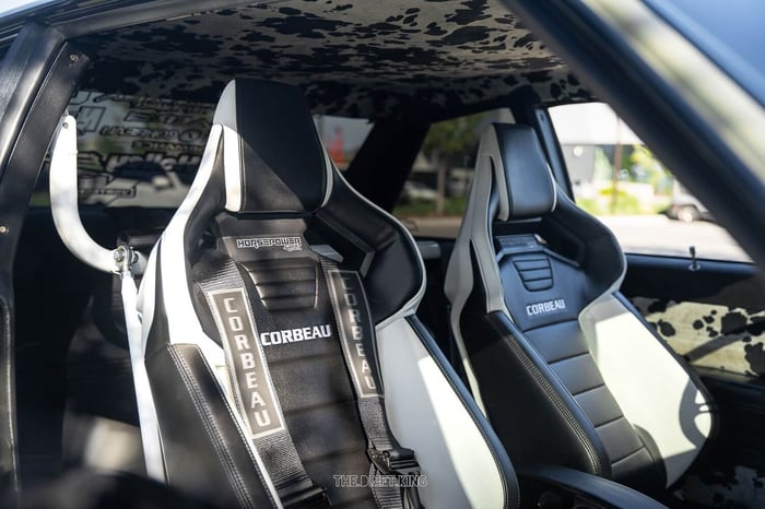 Interior view showing the cow-print upholstery and Corbeau seats, matching the car’s “Milk Money” nickname.