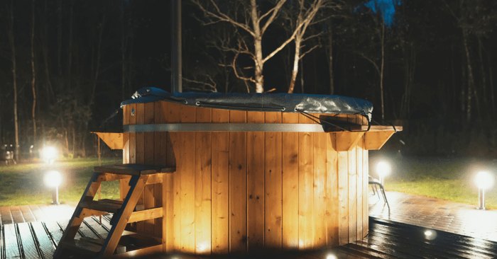 sauna vs hot tub shown by a wooden hot tub at night