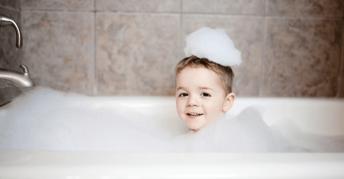 tub and shower with a cute boy in the midst of all the fluffy bubbles
