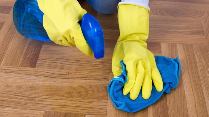 Cleaning around a parrot cage with spray and cloth as part of regular cage hygiene