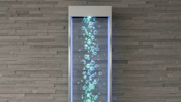 A unique and modern indoor wall fountain where illuminated bubbles rise through a clear panel, creating a dynamic visual effect.