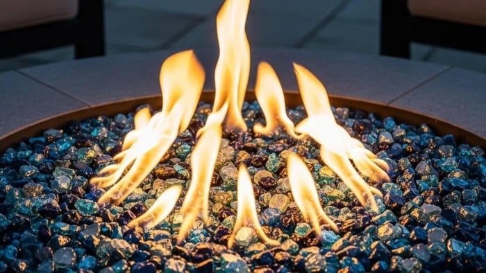 A beautiful fire pit at night, showcasing the illumination of blue fire glass by the warm, flickering flames.