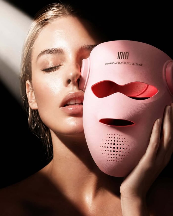 Close view of a pink INIA red light therapy mask and illuminated interior