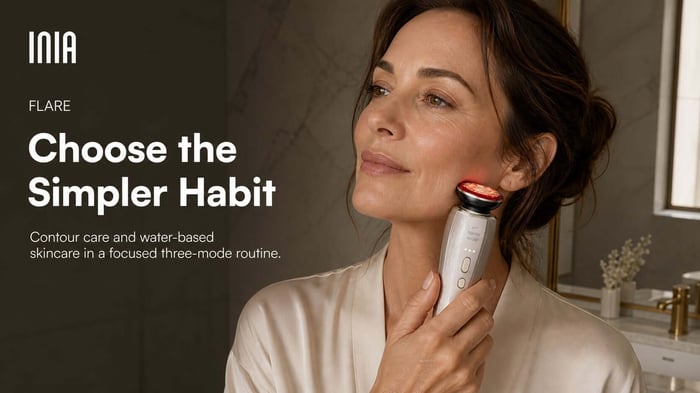 Woman gliding INIA FLARE upward along her jawline, with guidance to choose its simpler three-mode routine
