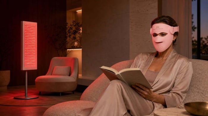 Woman wearing an INIA GLOW 4D LED mask with a red light panel in the room