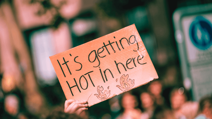 Protester holds 'It's getting hot in here' sign, echoing the theme of Feeling Overwhelmed by Climate Change blog post