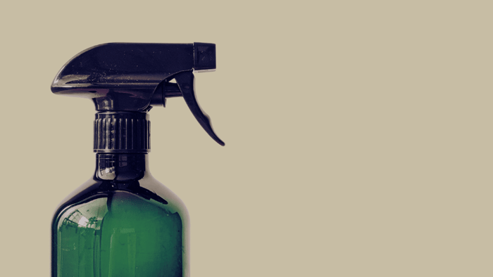 Green glass spray bottle representing the benefits of eco-friendly DIY cleaning spray