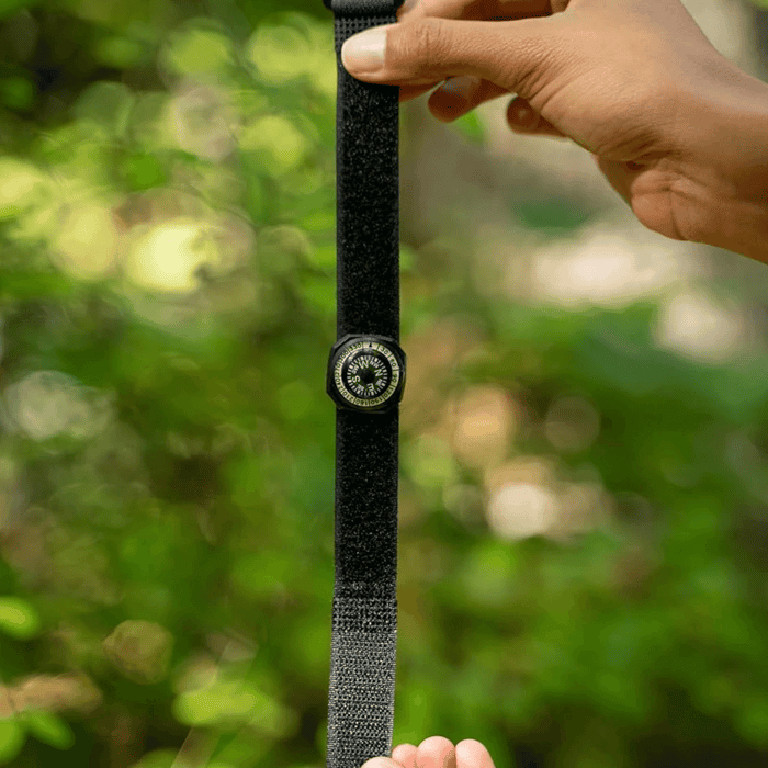 A Coghlans Wrist Compass spread out by two hands outdoors