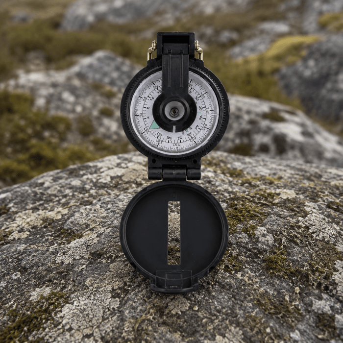 Coghlans Lensatic Compass sat on a rock outdoors