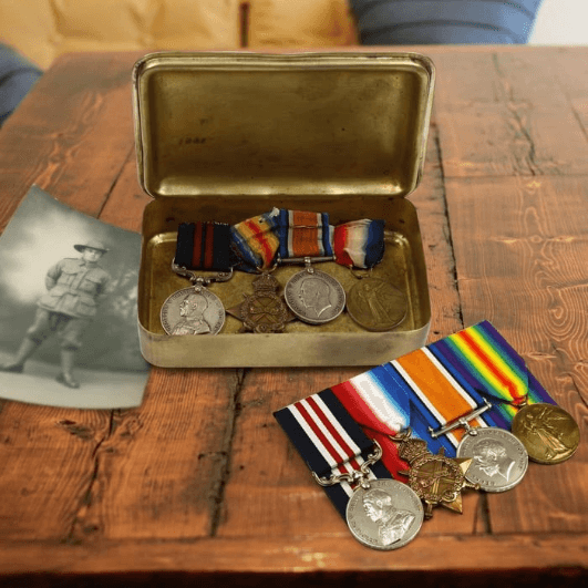 old worn out medals and new mounted medals next to old soldier's picture