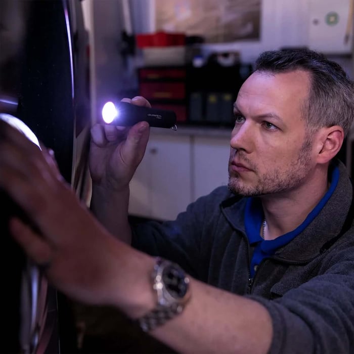 man working on car using a Ledlenser P7R Torch tactical flashlight