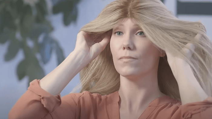 Image showing woman adjusting the wig so that ear tabs are aligned with your ears, ensuring a fit that is comfortable and secure.