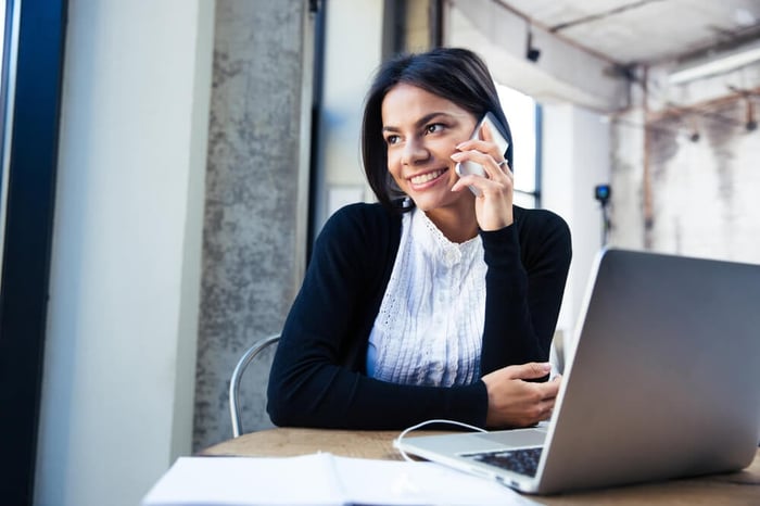 Happy businesswoman sitting at the table and talking on the phone in cafe. Looking away-2