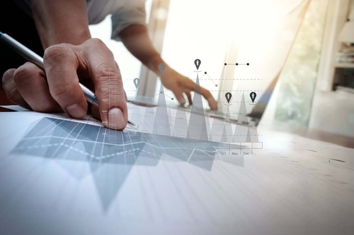 business documents on office table with smart phone and laptop computer and graph business with social network diagram and man working in the background