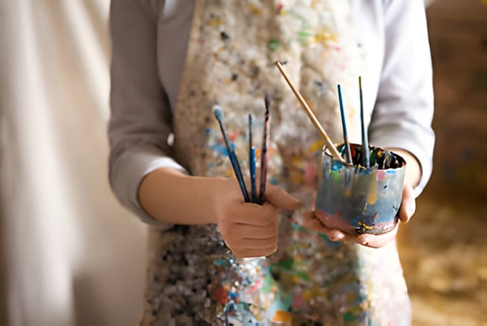 an artist holding paint brushes