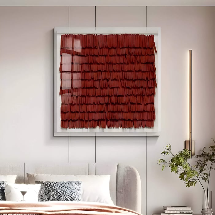 Square red leather wall panel with layered fringe-like strips hanging above an upholstered bed.