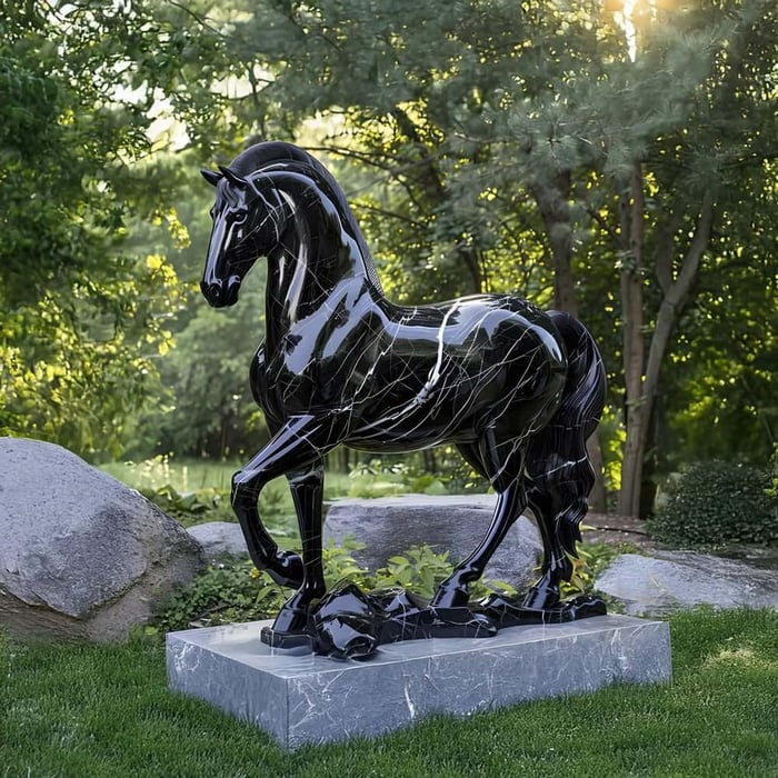 Glossy black marble horse statue standing on a stone base in a leafy garden.