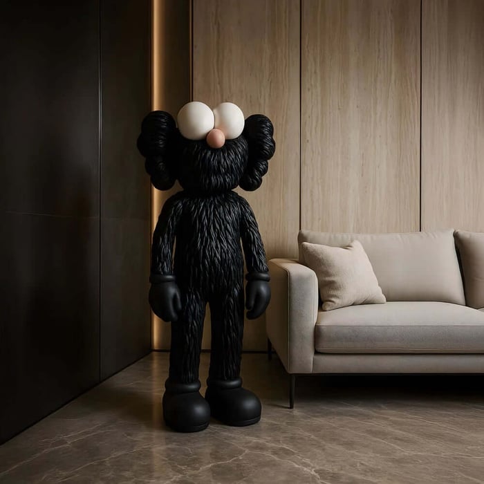 Tall black furry Iconify sculpture standing next to a beige sofa in a minimalist living room.