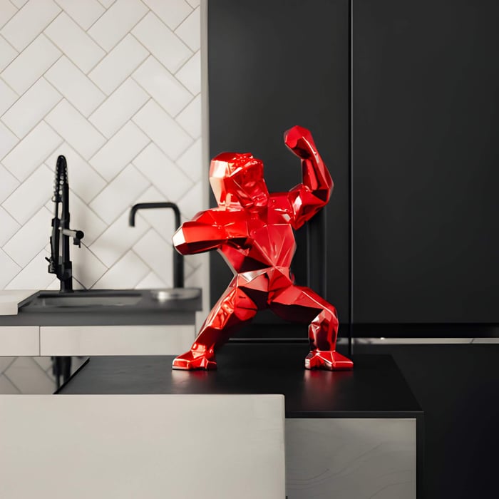 50cm Fire Red Gorilla Sculpture placed on a modern kitchen counter, adding a bold pop of color against sleek black and white decor.
