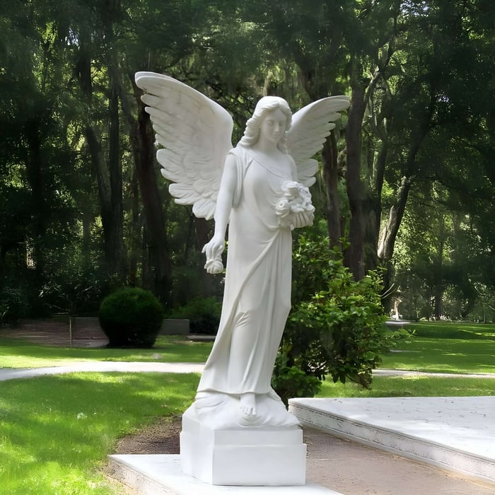 White angel statue holding flowers in lush garden