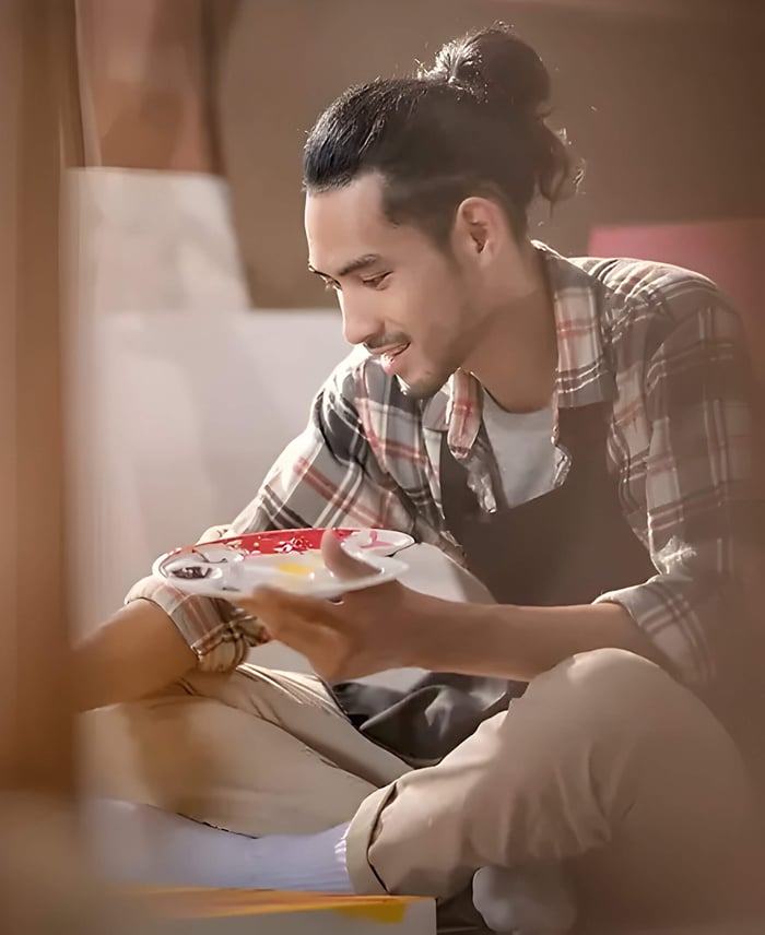 a man sitting crossed legs holding a paint pallet