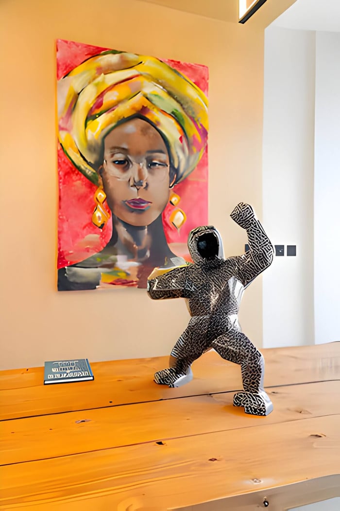 a magma gorilla sculpture on a wooden table with artwork behind