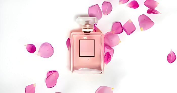 a bottle of pink perfume with pink rose petals surrounding