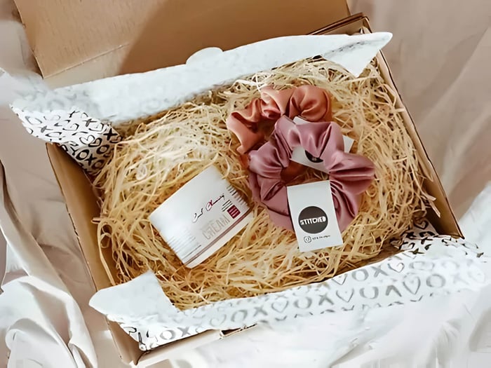 a cardboard hamper box with stuffing and silk scrunchies and body cream