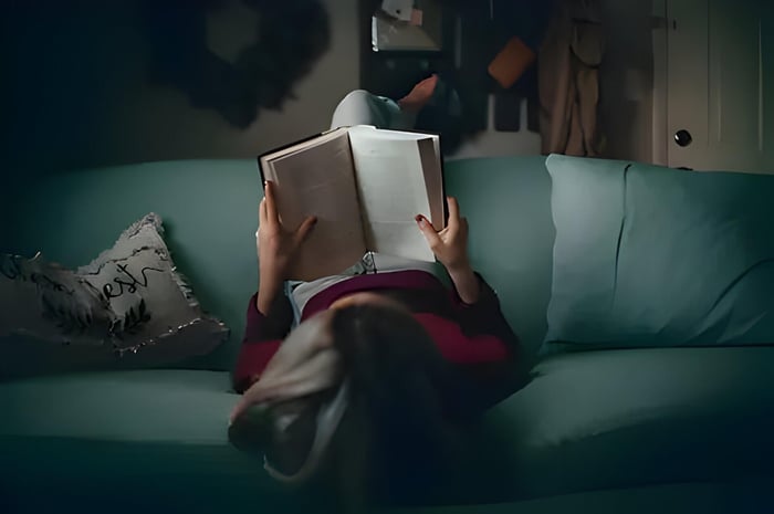 an Ariel view on a lady on a green sofa reading a book