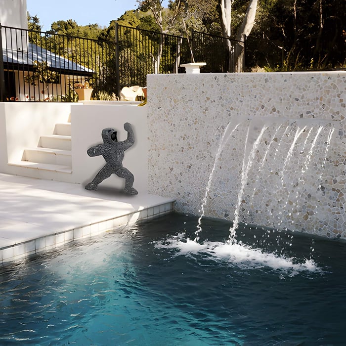a gorilla sculpture next to a garden water feature