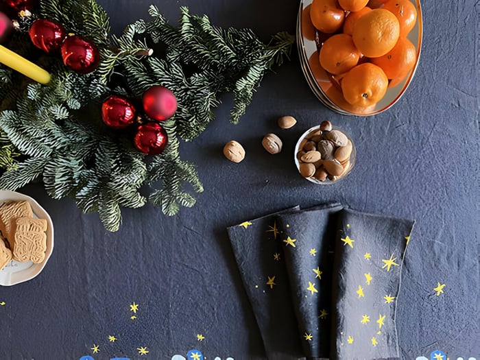 A Christmas tables with oranges, fir tree and baubles with navy linen napkins