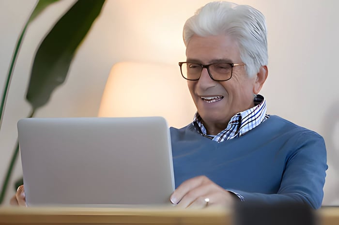 An older gentleman using a laptop and smiling