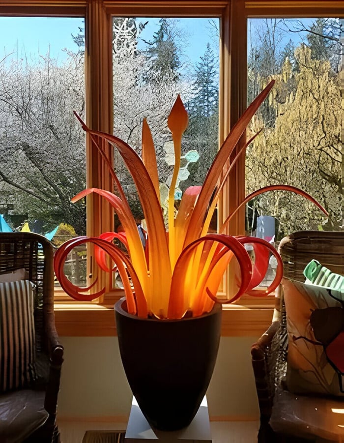 an orange and red hand blown glass art sculpture in a conservatory