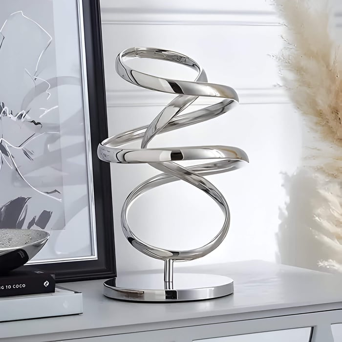 a silver coloured swirly sculpture on a mantel piece