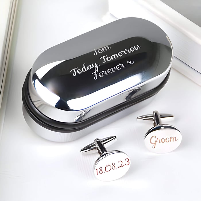 2 engraved cufflinks next to a silver case with an engraved message on top