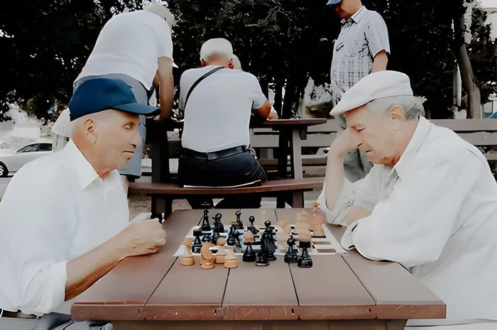 2 elderly men playing chess on a park bench