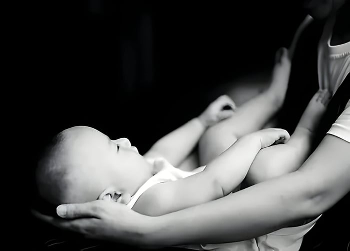 A black and white photo of a baby in its mothers arms
