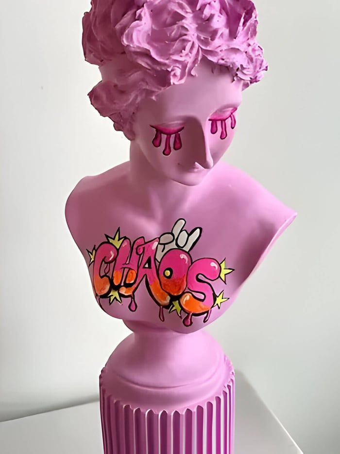 a neon pink bust sculpture with pop art style writing and drawing