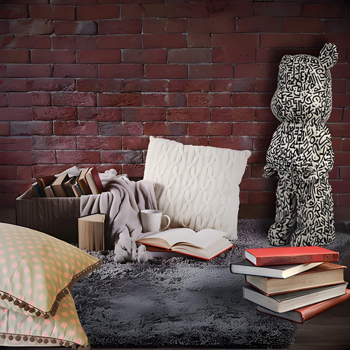 a scribble bear inside a cosy nook setting with a red brick wall and cushions