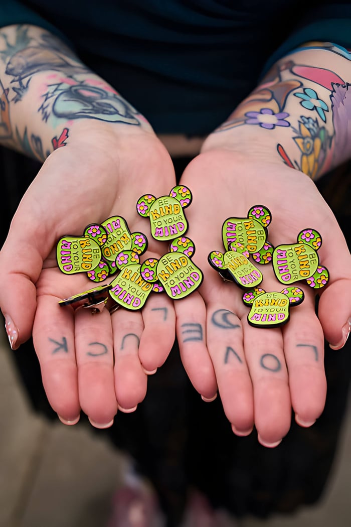 Hands holding out pin badges for the darlington bear trail