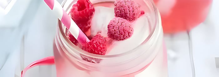 a pink cocktail with frozen raspberries on top