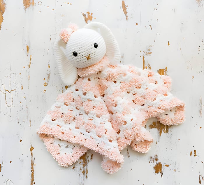 a pink and white baby crochet blanket with a rabbit design