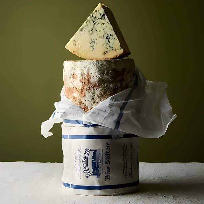 a wedge of stilton cheese resting on the wheel