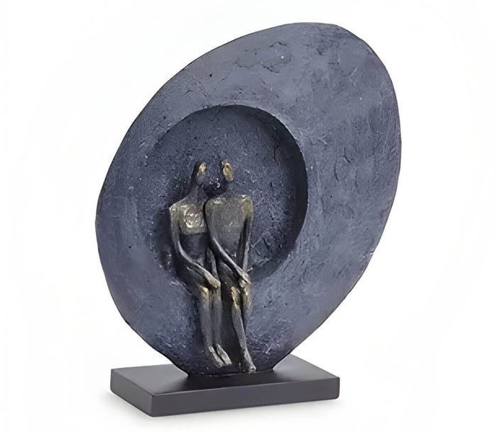 a bronze abstract sculpture of a couple sitting in an oval seat