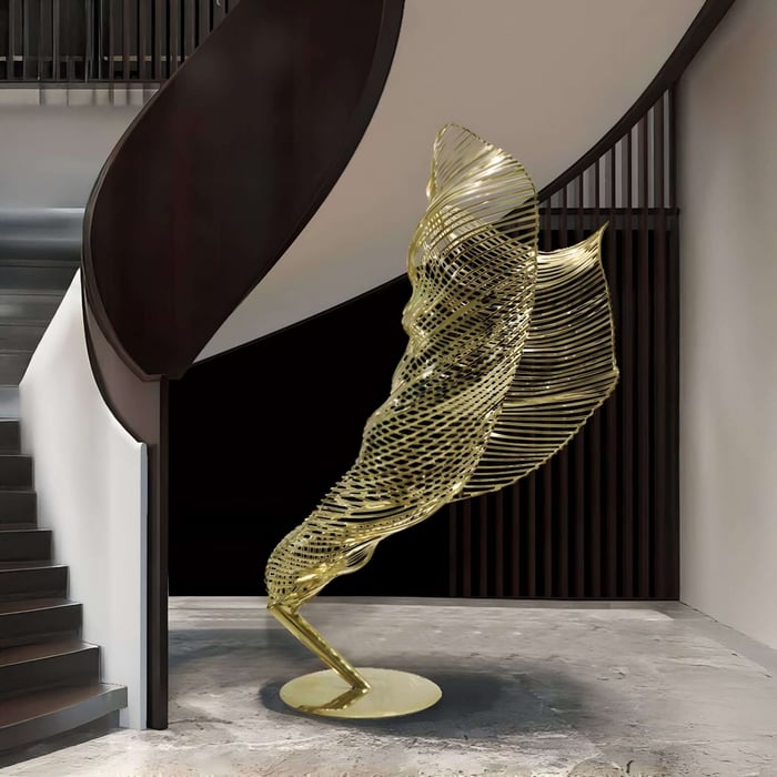 Flowing golden wireframe sculpture at the base of a spiral staircase.