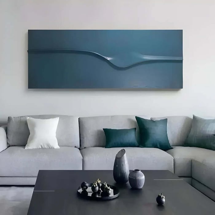 Long teal minimalist wall art panel with sculpted wave detail above a grey corner sofa and dark coffee table.