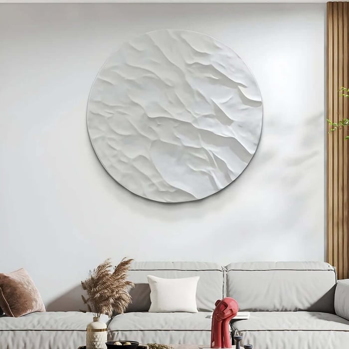 Textured white circular wall art above a grey sofa, creating a clean and calming minimalist look.