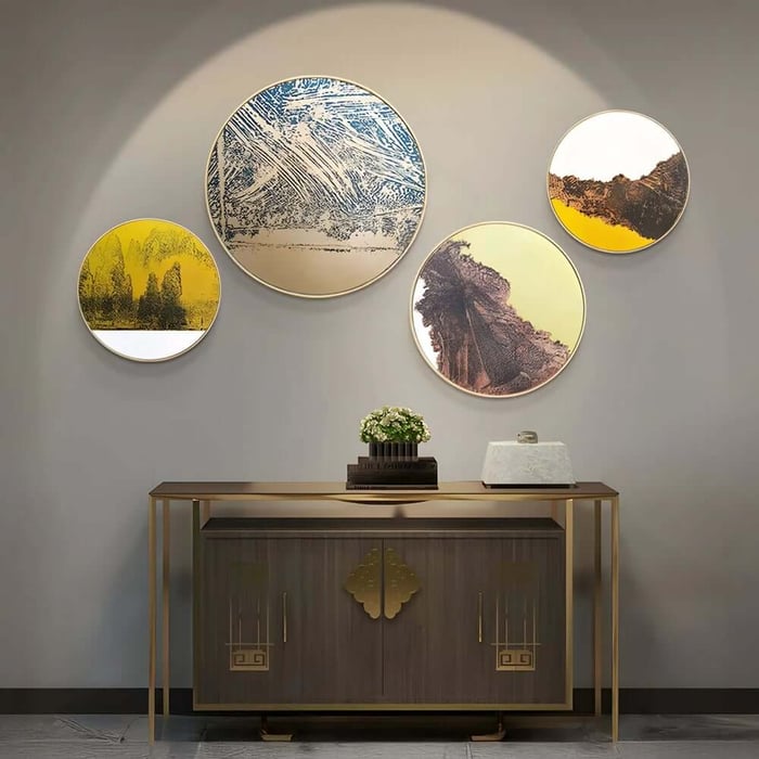 Set of three round abstract landscape artworks in blue, yellow and earthy brown tones above a console table in a contemporary hallway.